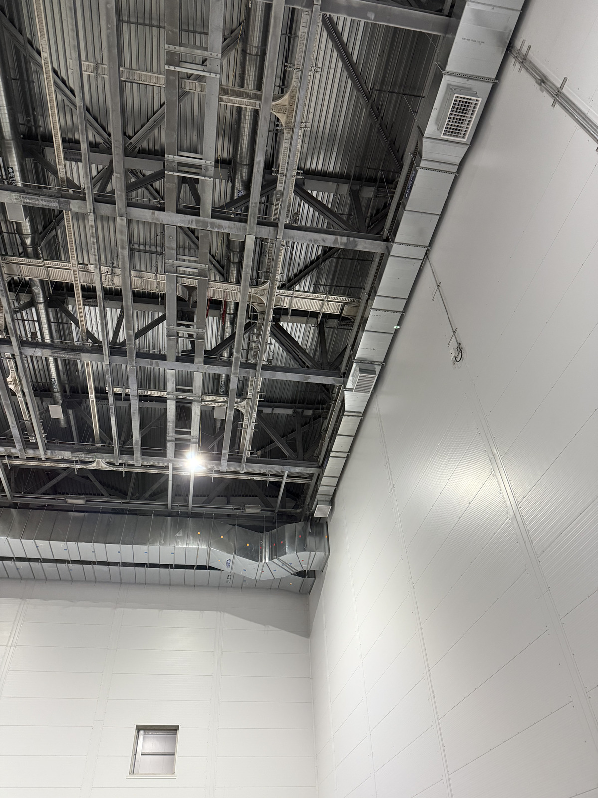 Galvanized rectangular HVAC supply mains and branch duct runs installed under a steel roof deck