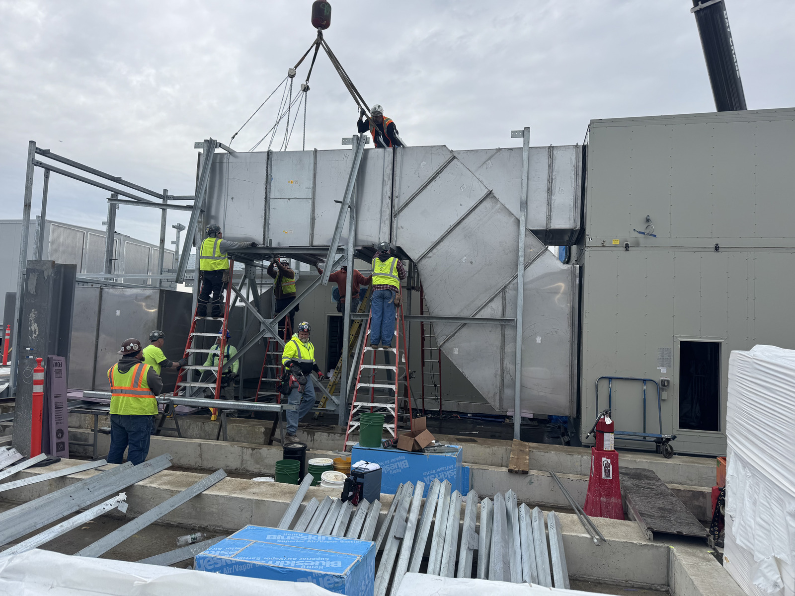 Union crew assembling a large rooftop air handler plenum from sheet metal panels